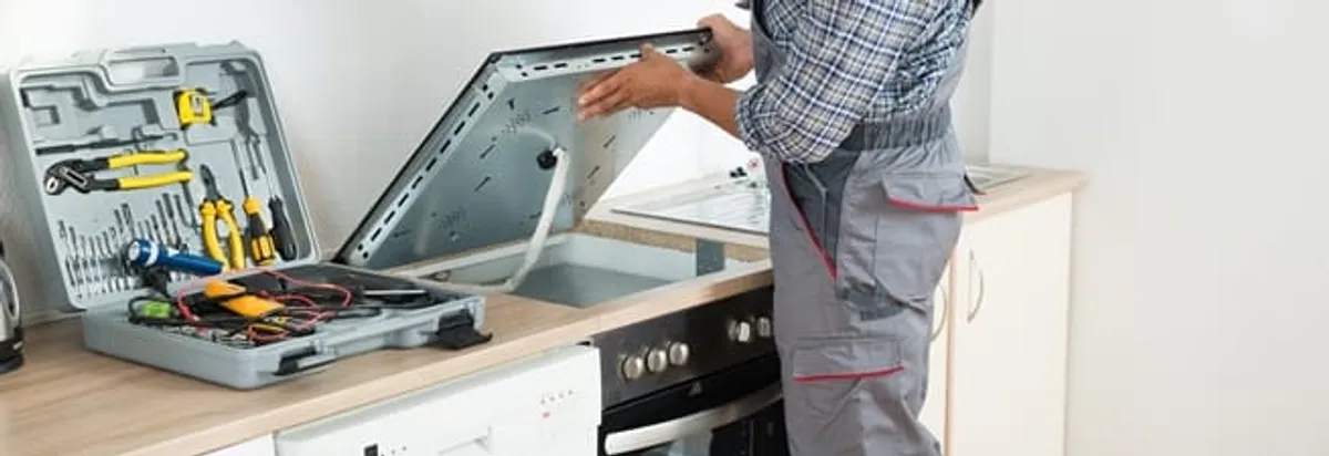 Cooktop repair technician lifting a built-in stovetop for service in Stockton, CA