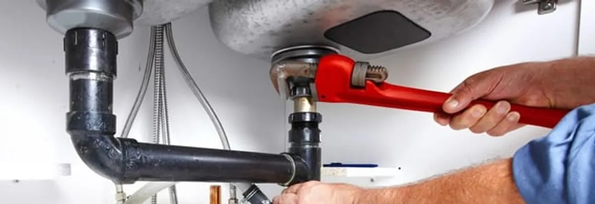 Garbage disposal repair technician tightening the sink drain and disposal connection in Stockton, CA