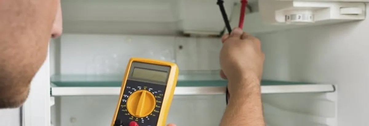Refrigerator repair technician testing electrical components with a multimeter in Stockton, CA