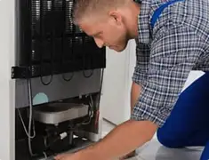 Refrigerator repair technician servicing the compressor and condenser area in Stockton, CA
