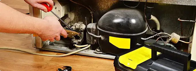 Refrigerator repair technician fixing the compressor and wiring in Stockton, CA